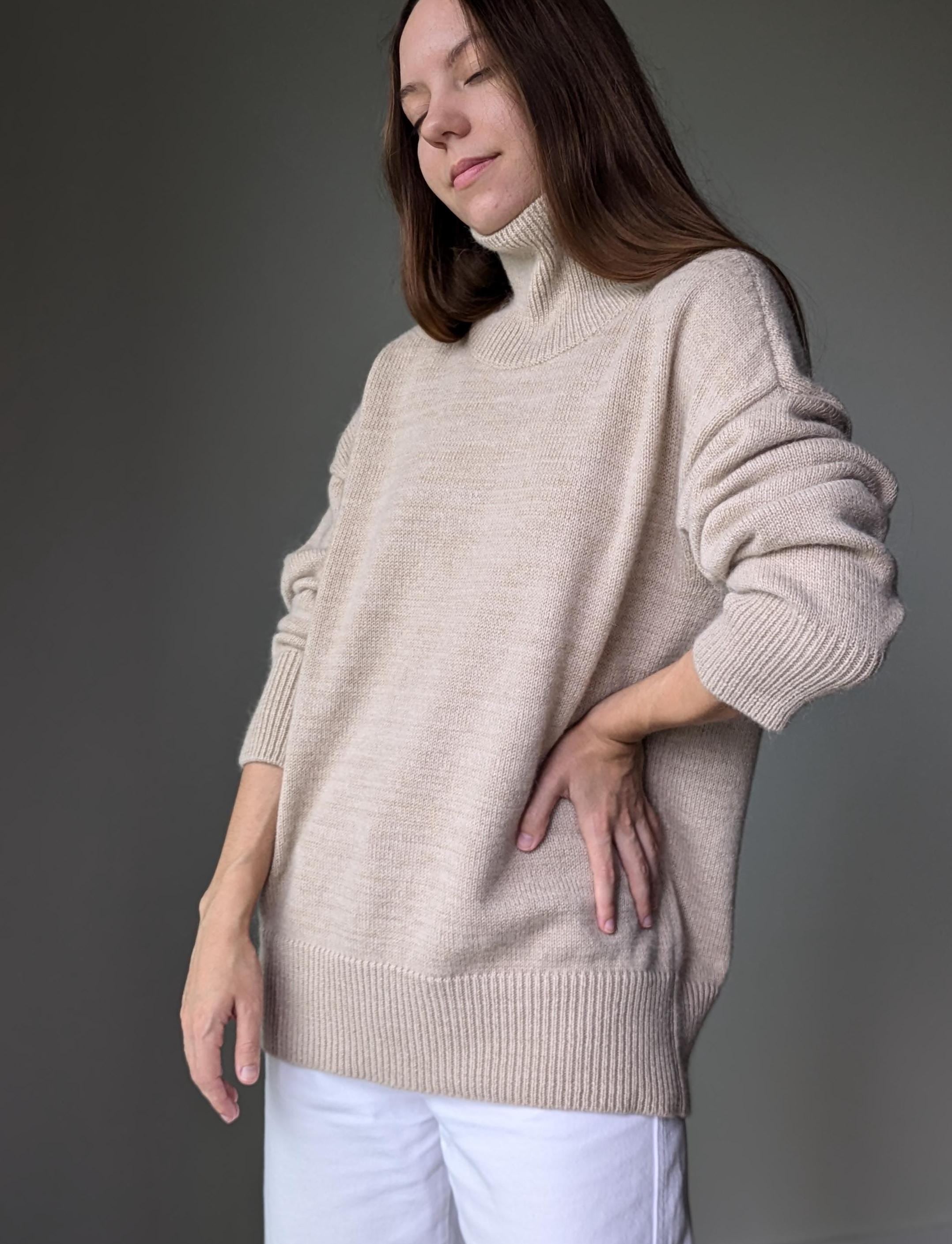 Sand woman wearing a beige sweater against a gray background