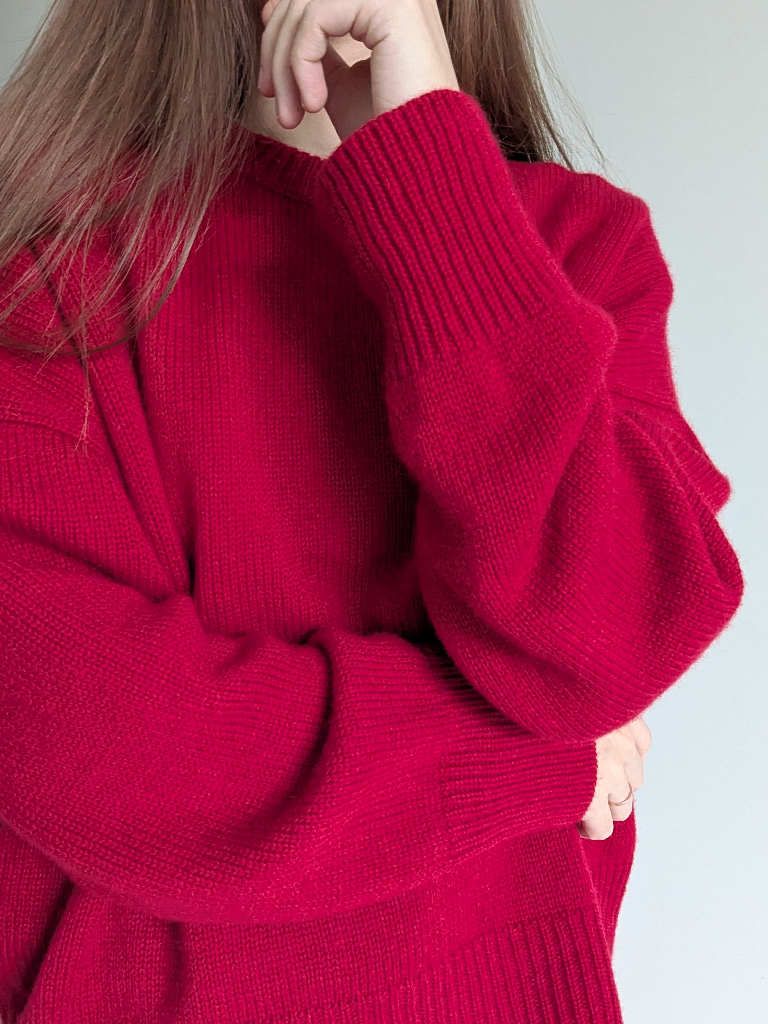 Red sweater worn by a person on a plain background