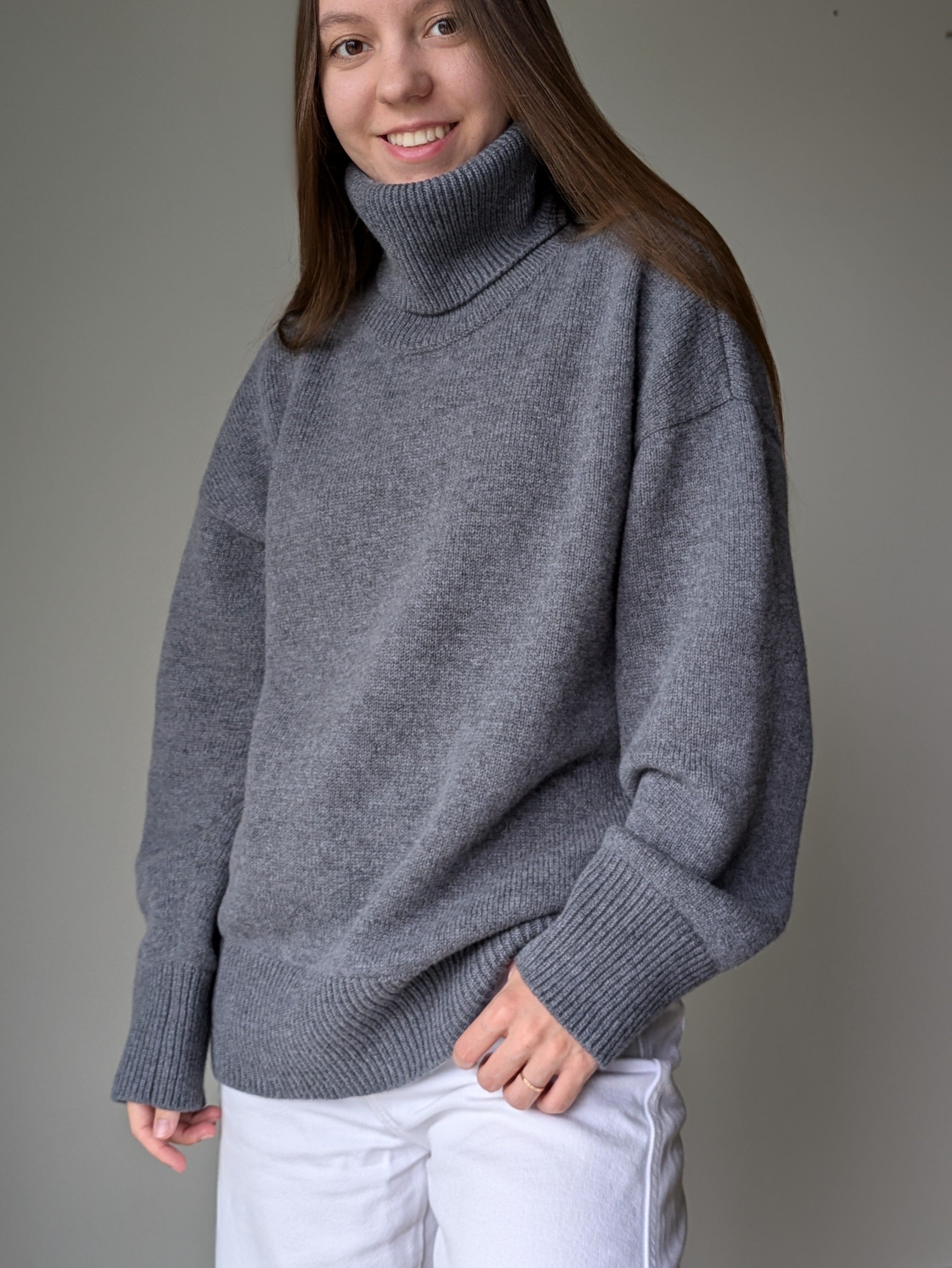 Gray Person wearing a gray turtleneck sweater against a plain background