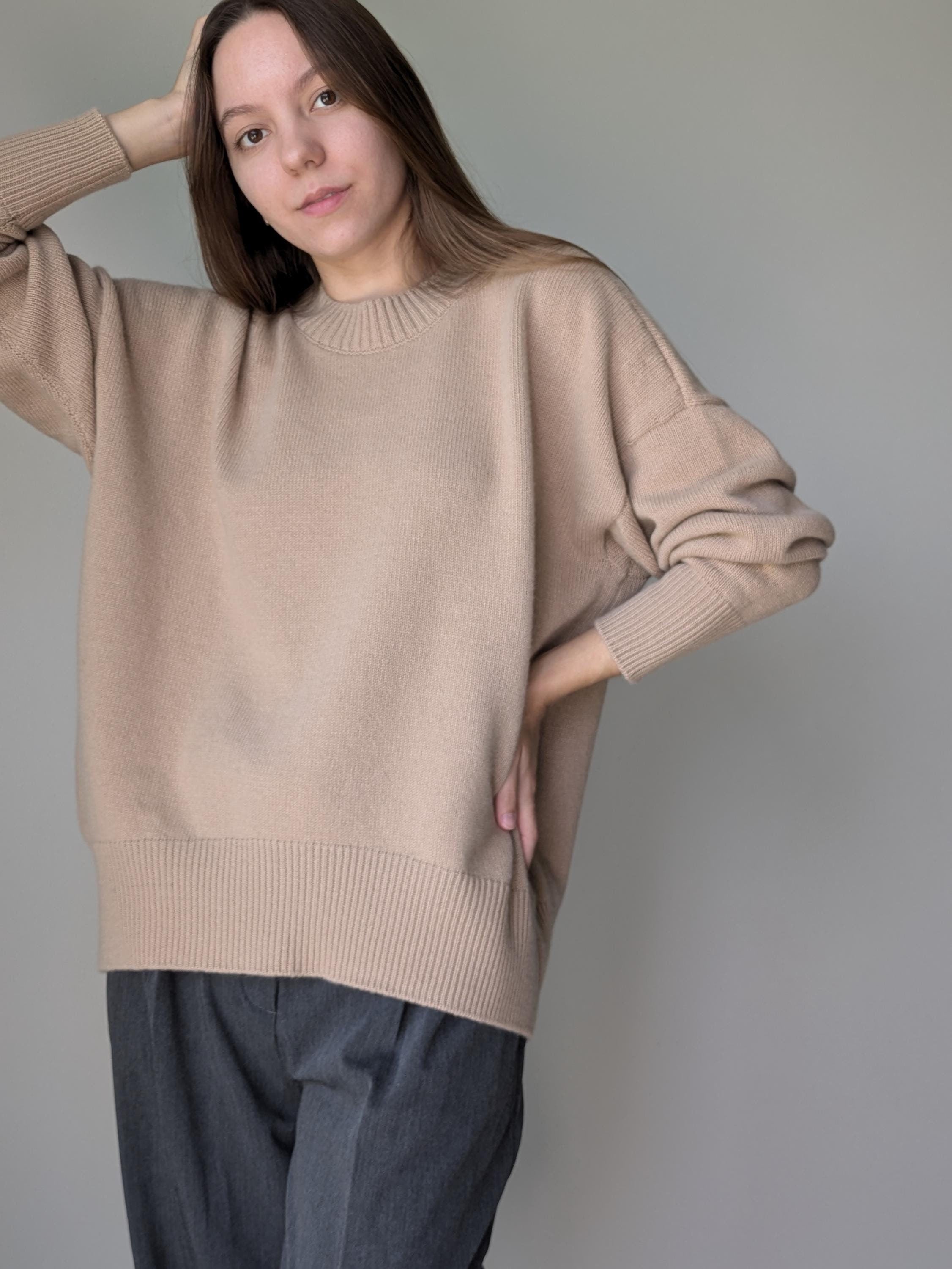 Woman wearing a beige sweater against a plain background