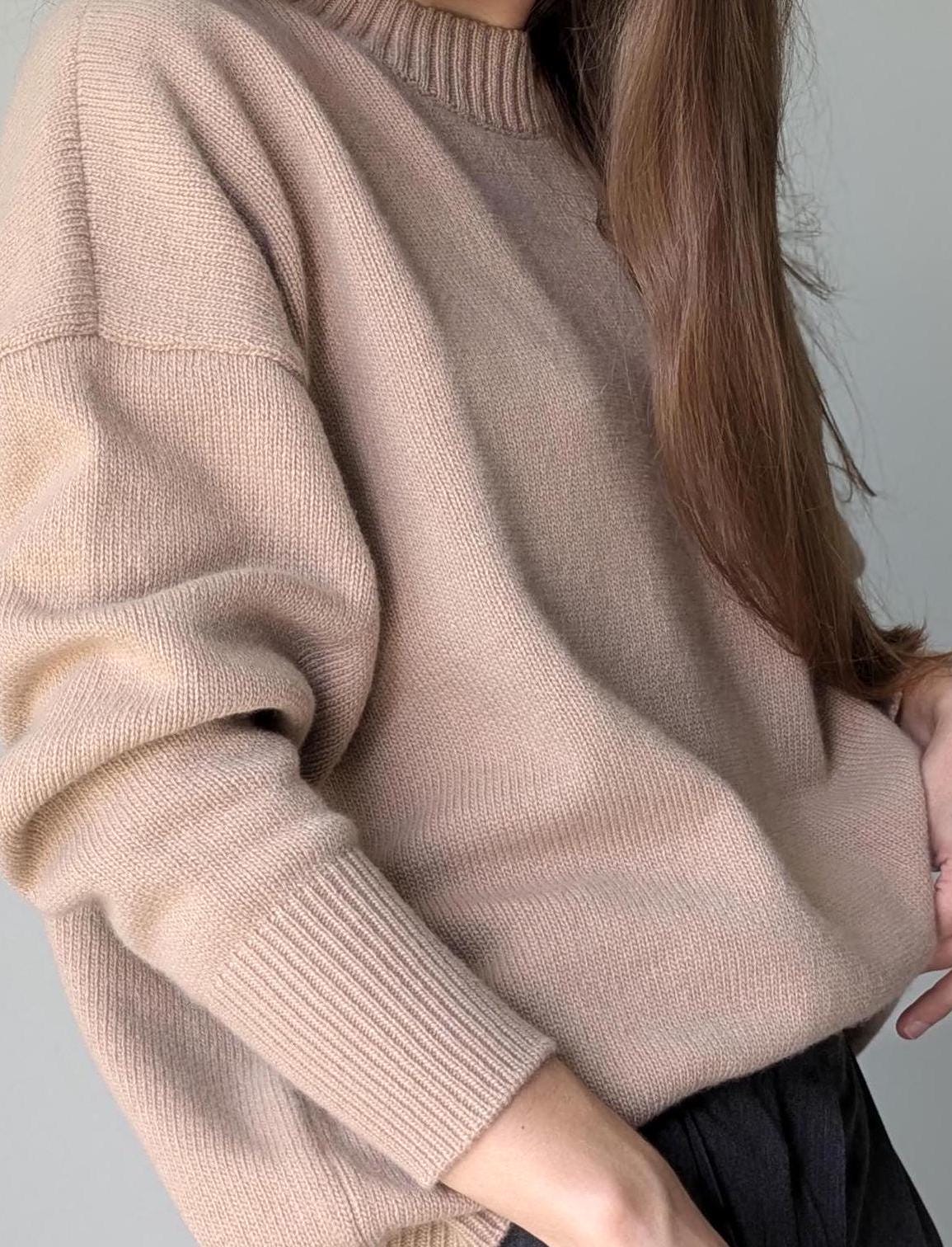 Beige sweater worn by a person on a gray background