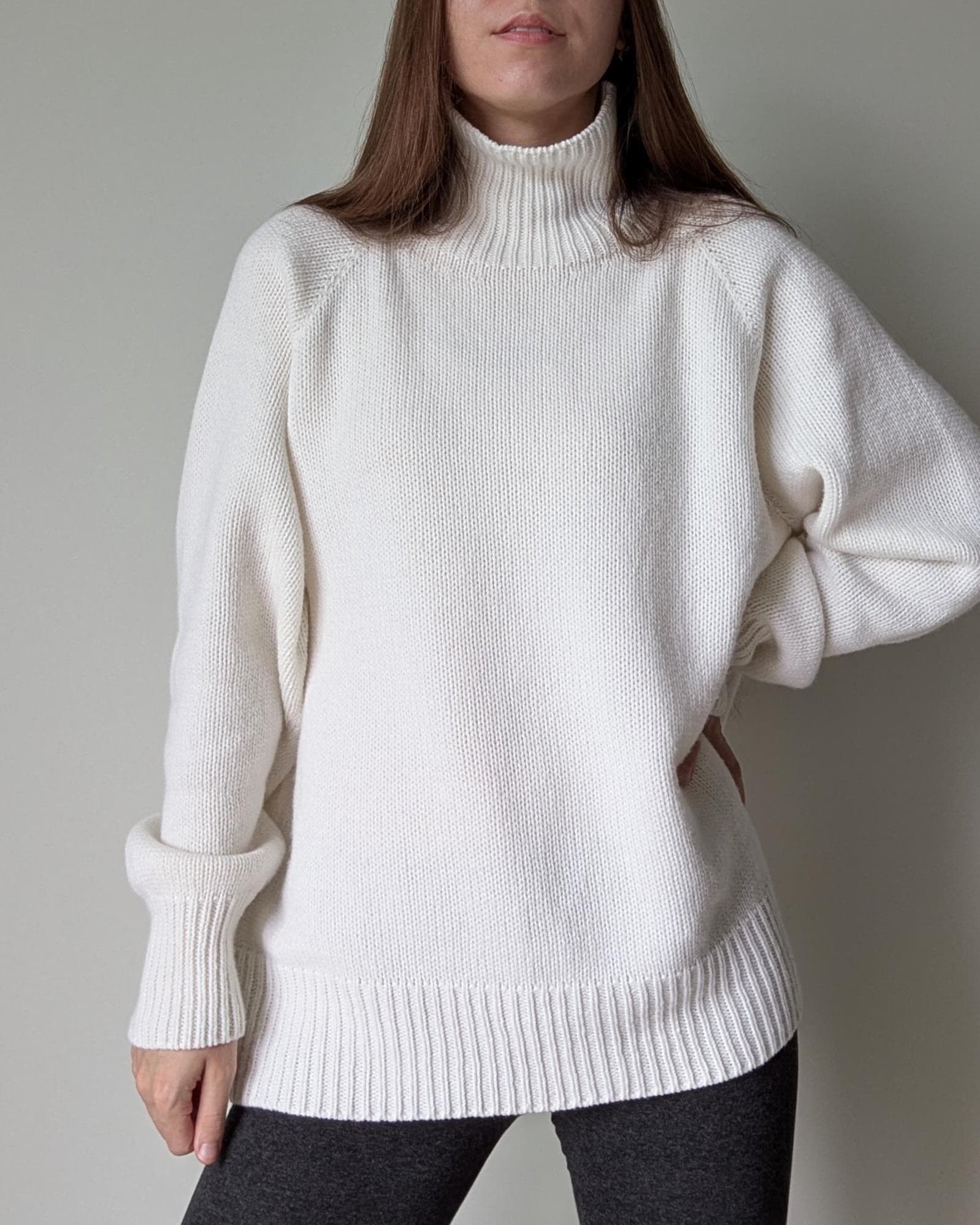 White Person wearing a white turtleneck sweater against a plain background