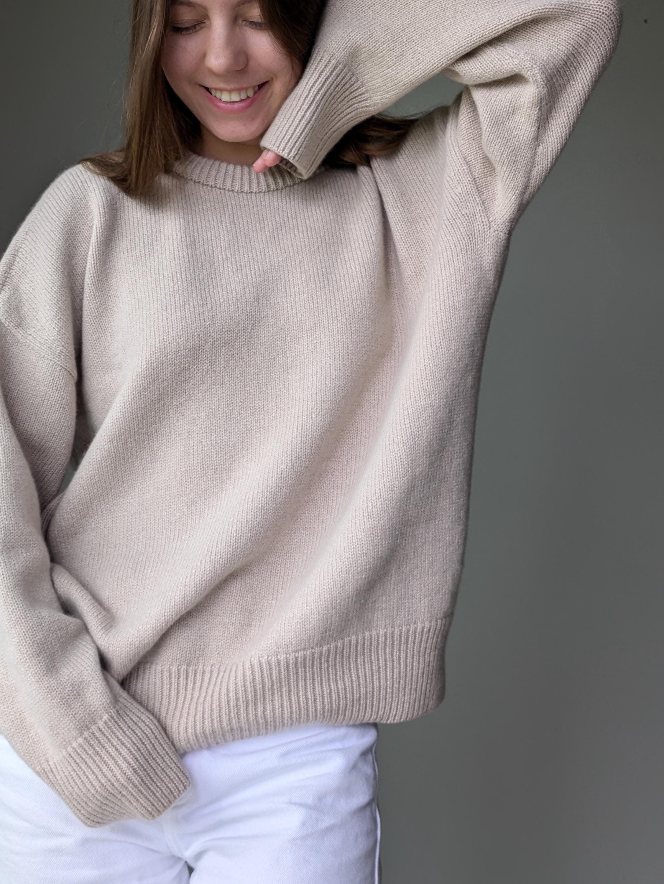 Person wearing a beige sweater against a gray background