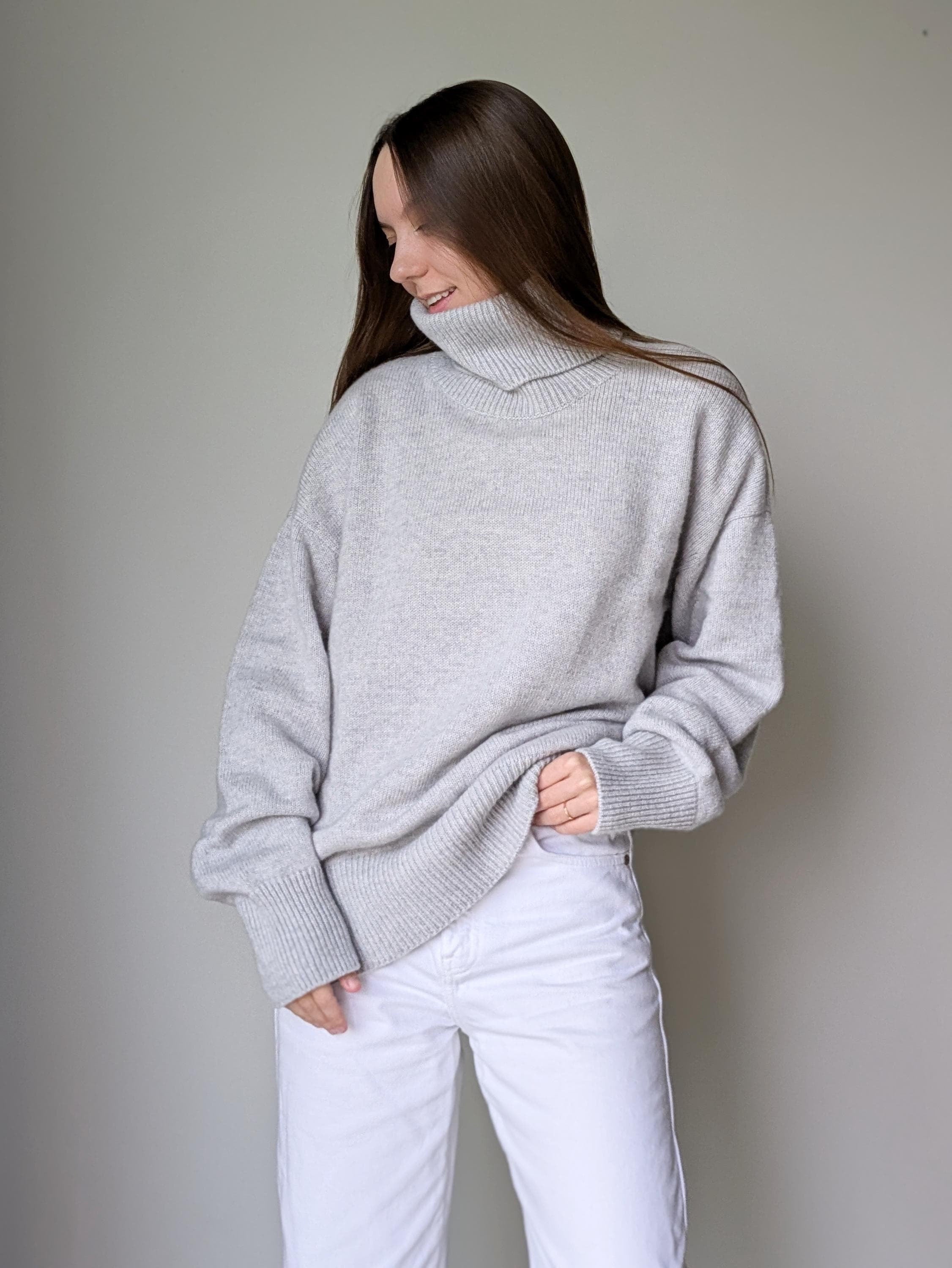 Pearl_gray Woman wearing a gray sweater and white pants against a plain background