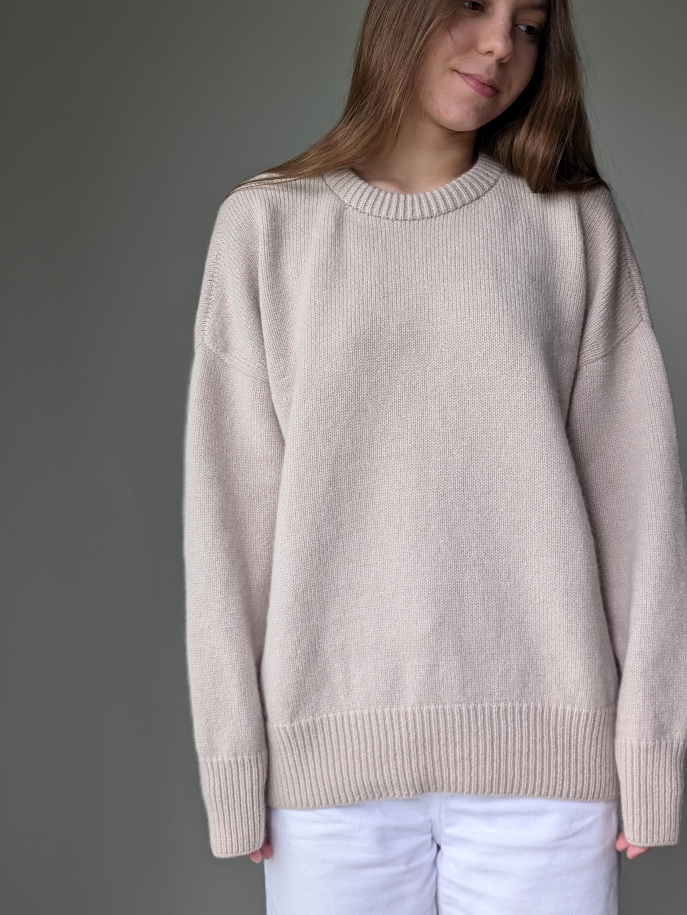 Woman wearing a beige sweater against a gray background