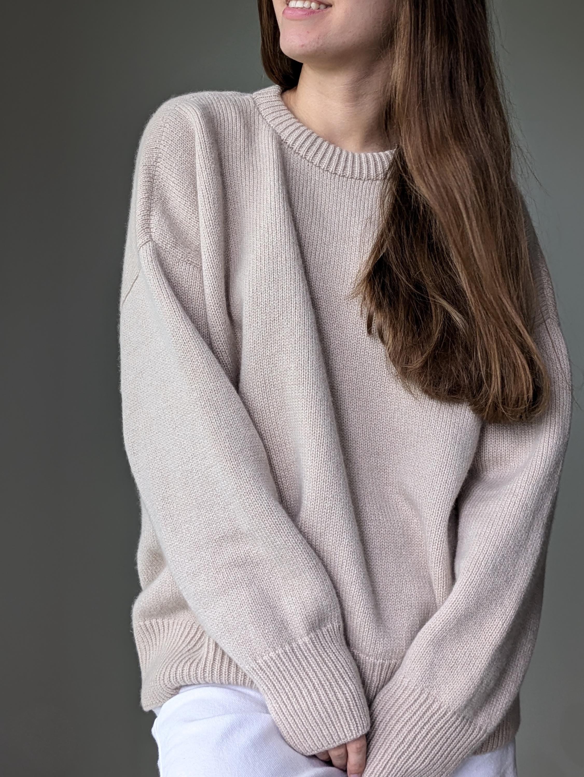 Person wearing a beige sweater against a gray background