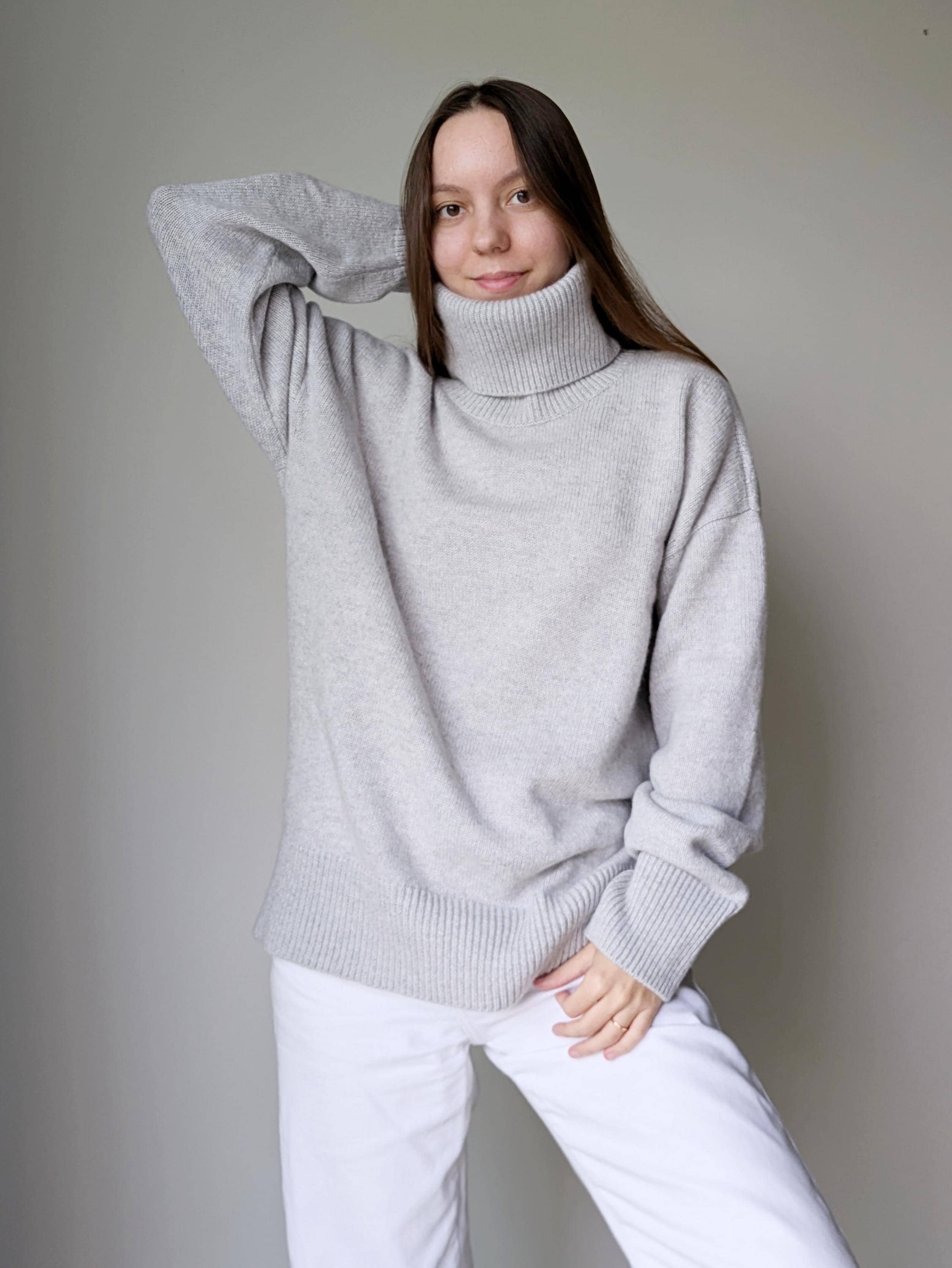 Pearl_gray Woman wearing a gray sweater and white pants against a plain background
