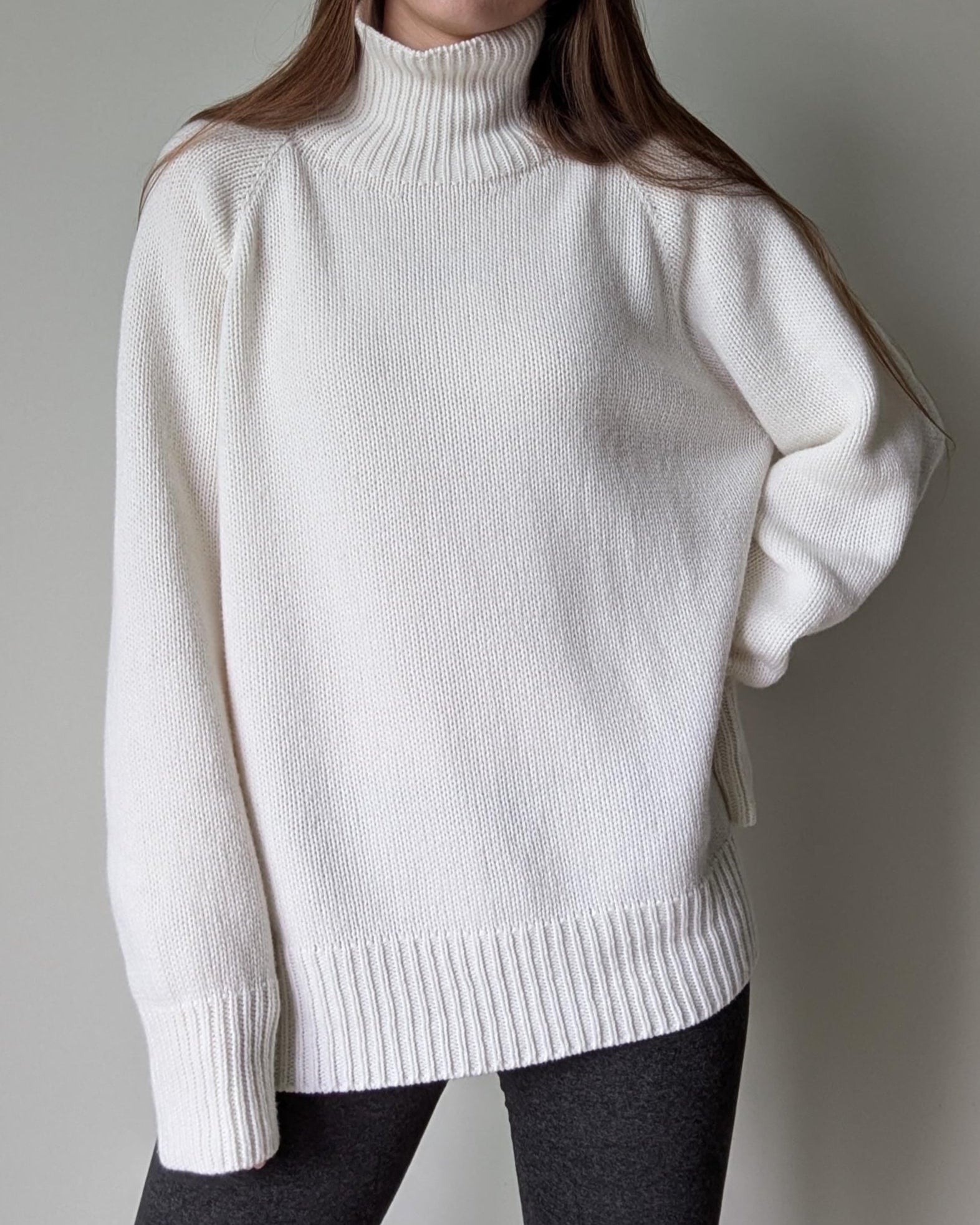 White turtleneck sweater worn by a person on a plain background