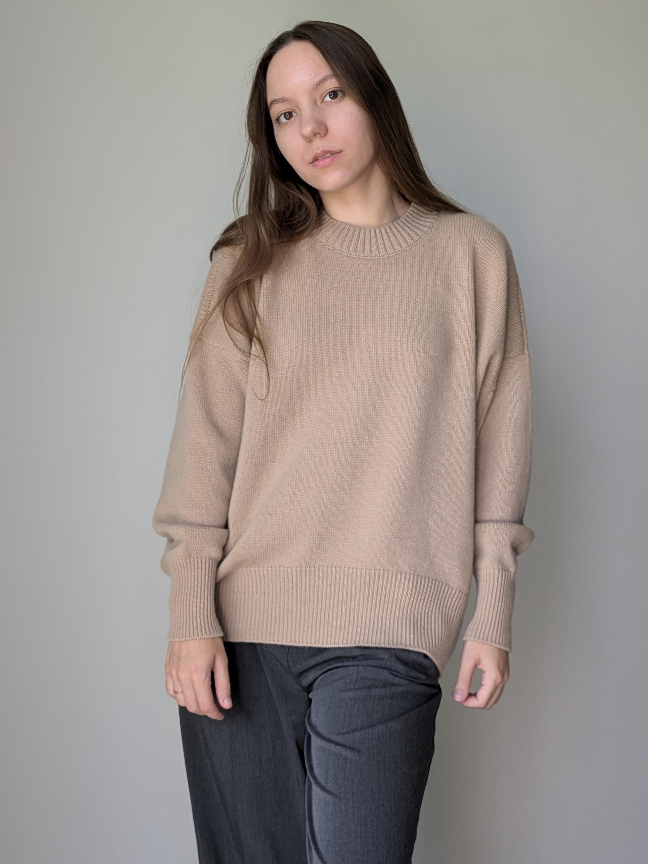 Woman wearing a beige sweater against a plain background