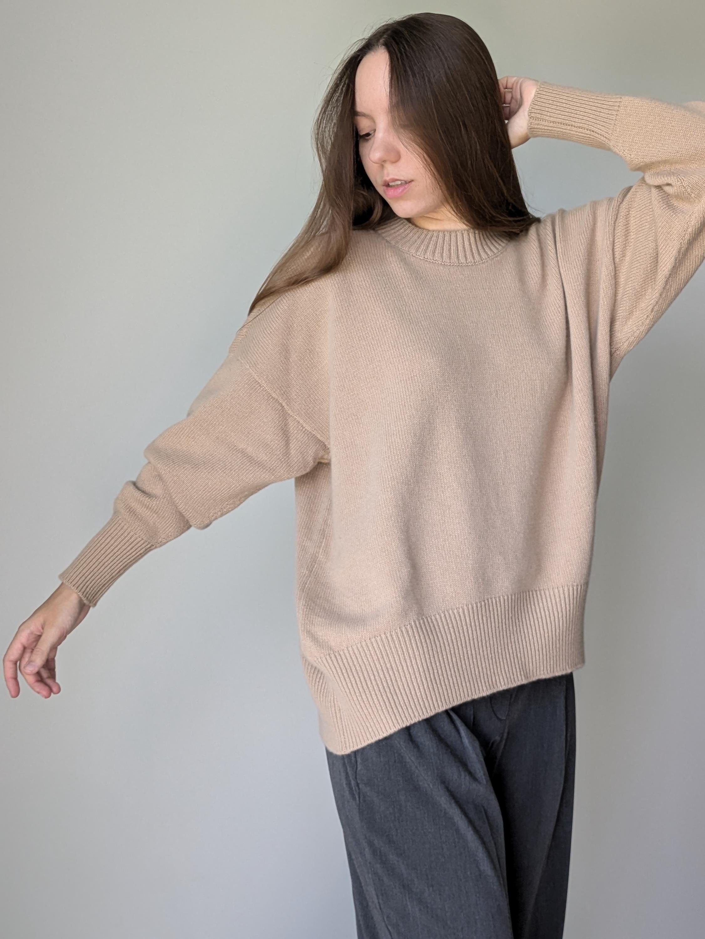 Woman wearing a beige sweater against a plain background