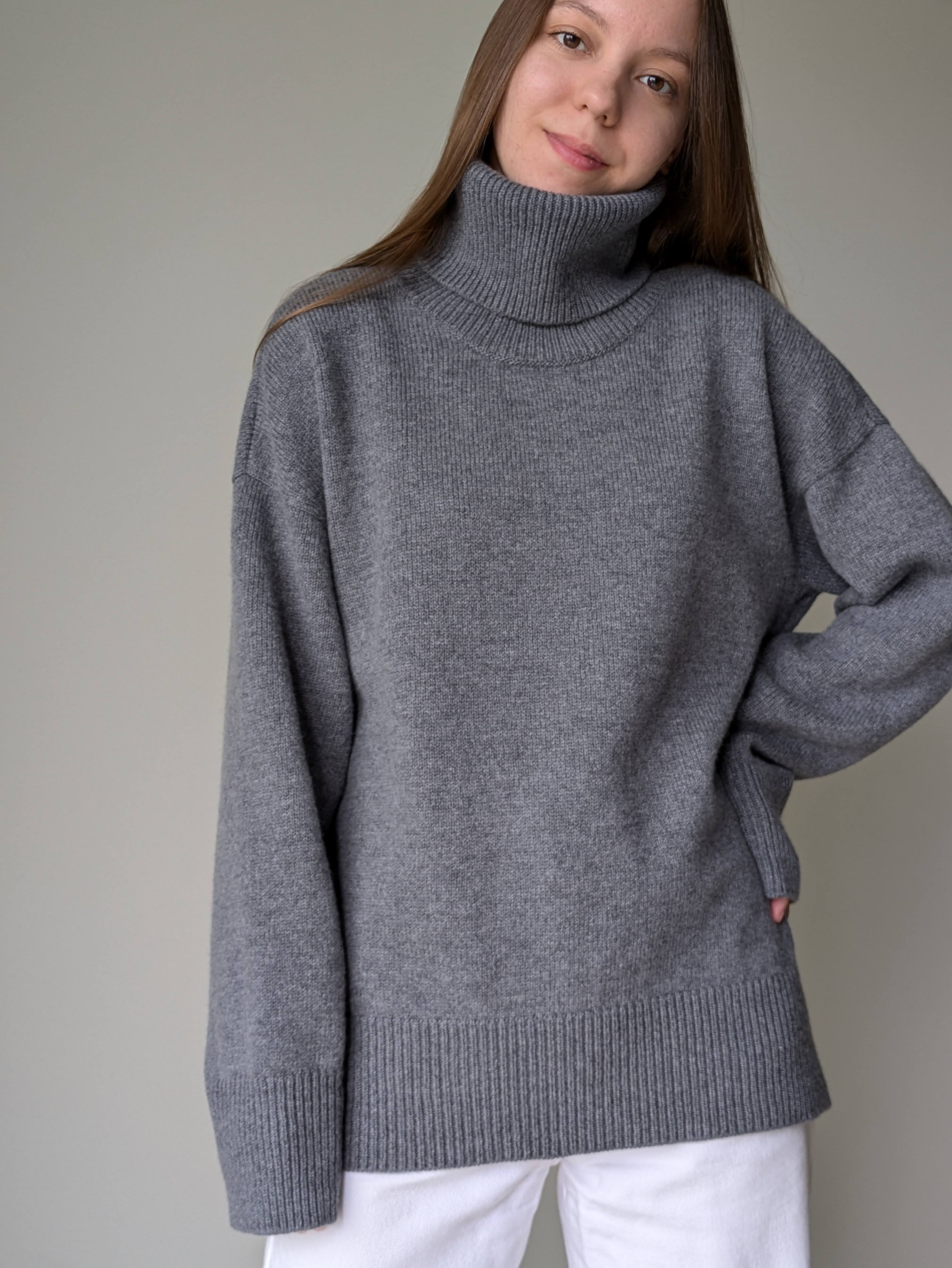 Gray Person wearing a gray turtleneck sweater against a plain background