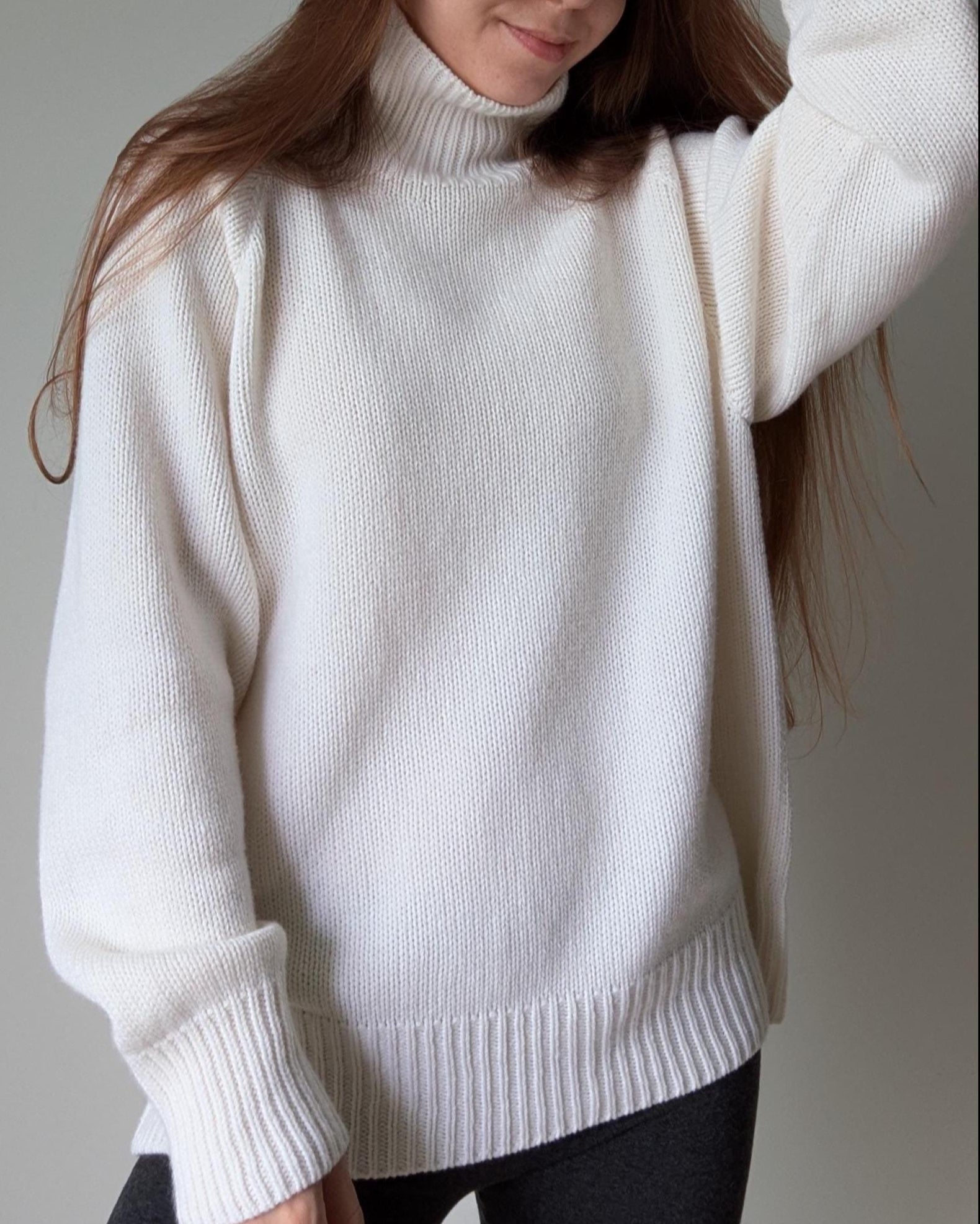 White Person wearing a white turtleneck sweater against a neutral background