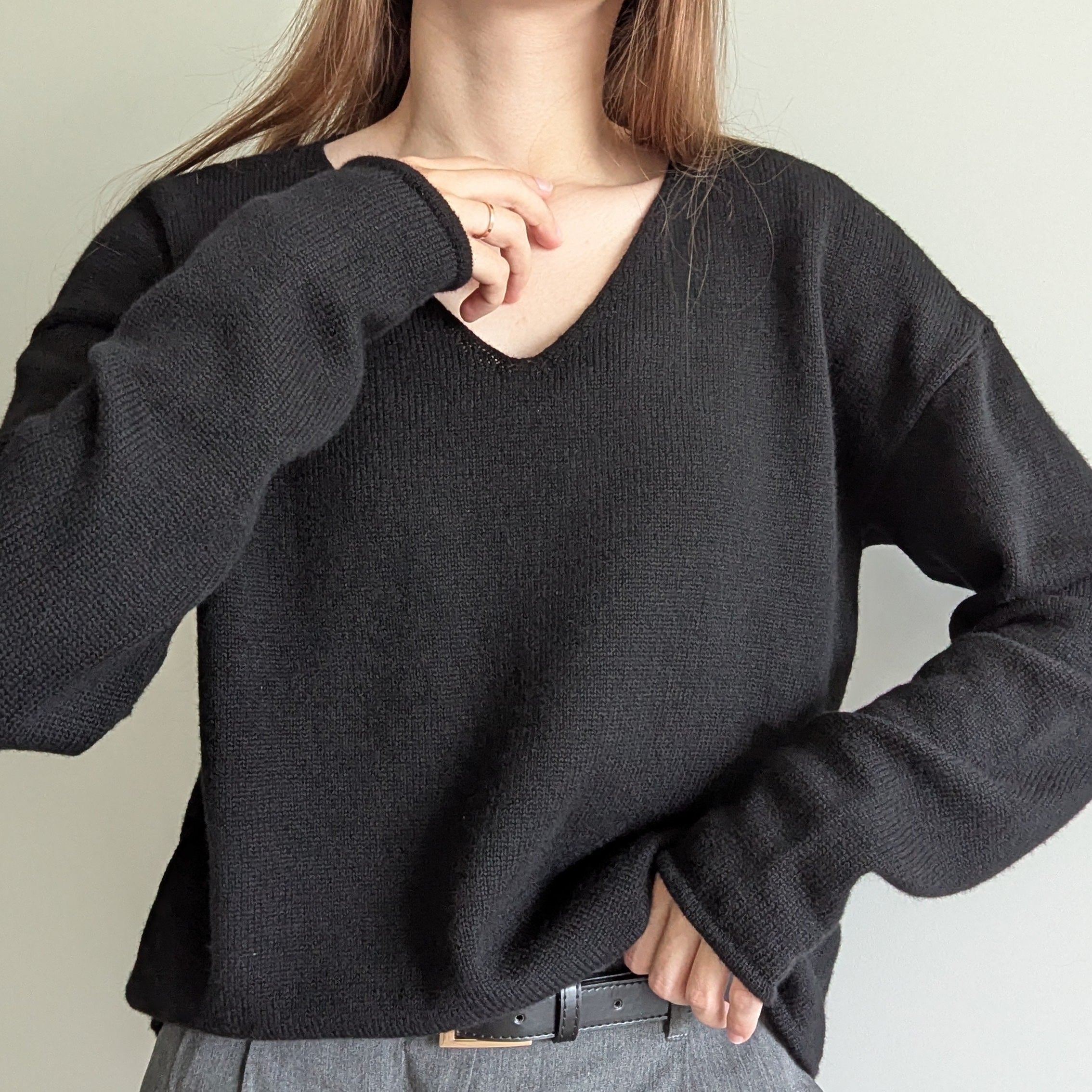 Black Person wearing a black sweater against a plain background