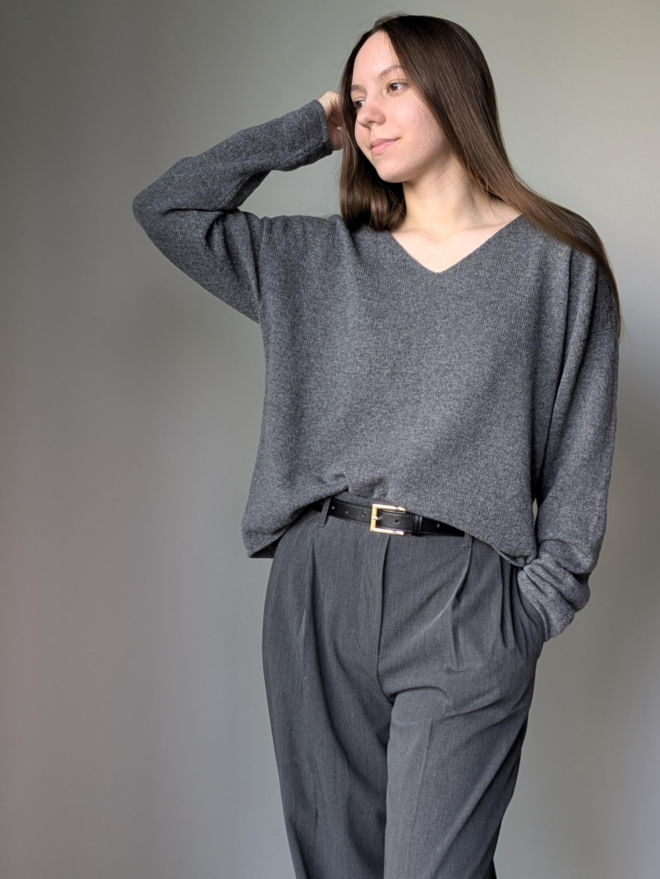 Gray Person wearing a gray sweater and pants against a plain background