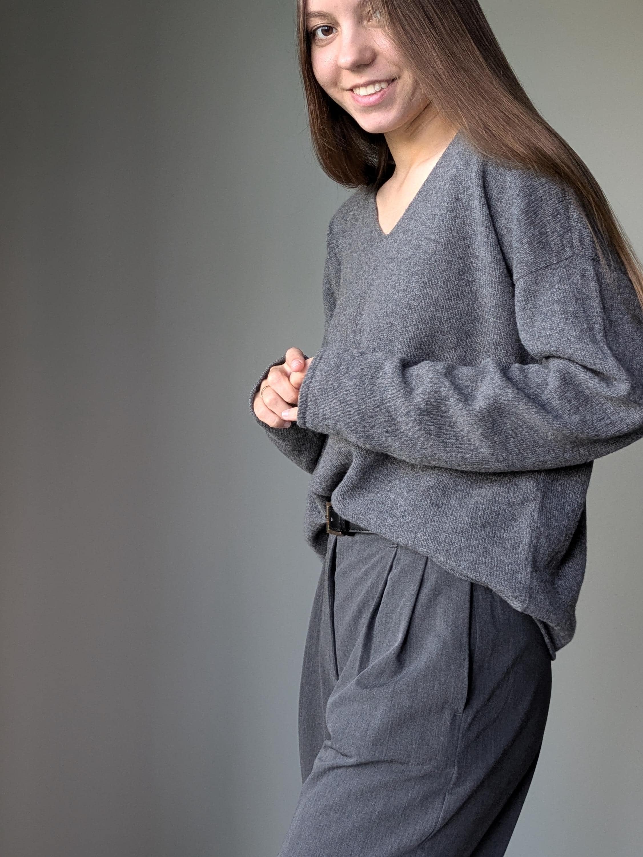 Gray Person wearing a gray sweater and pants against a plain background