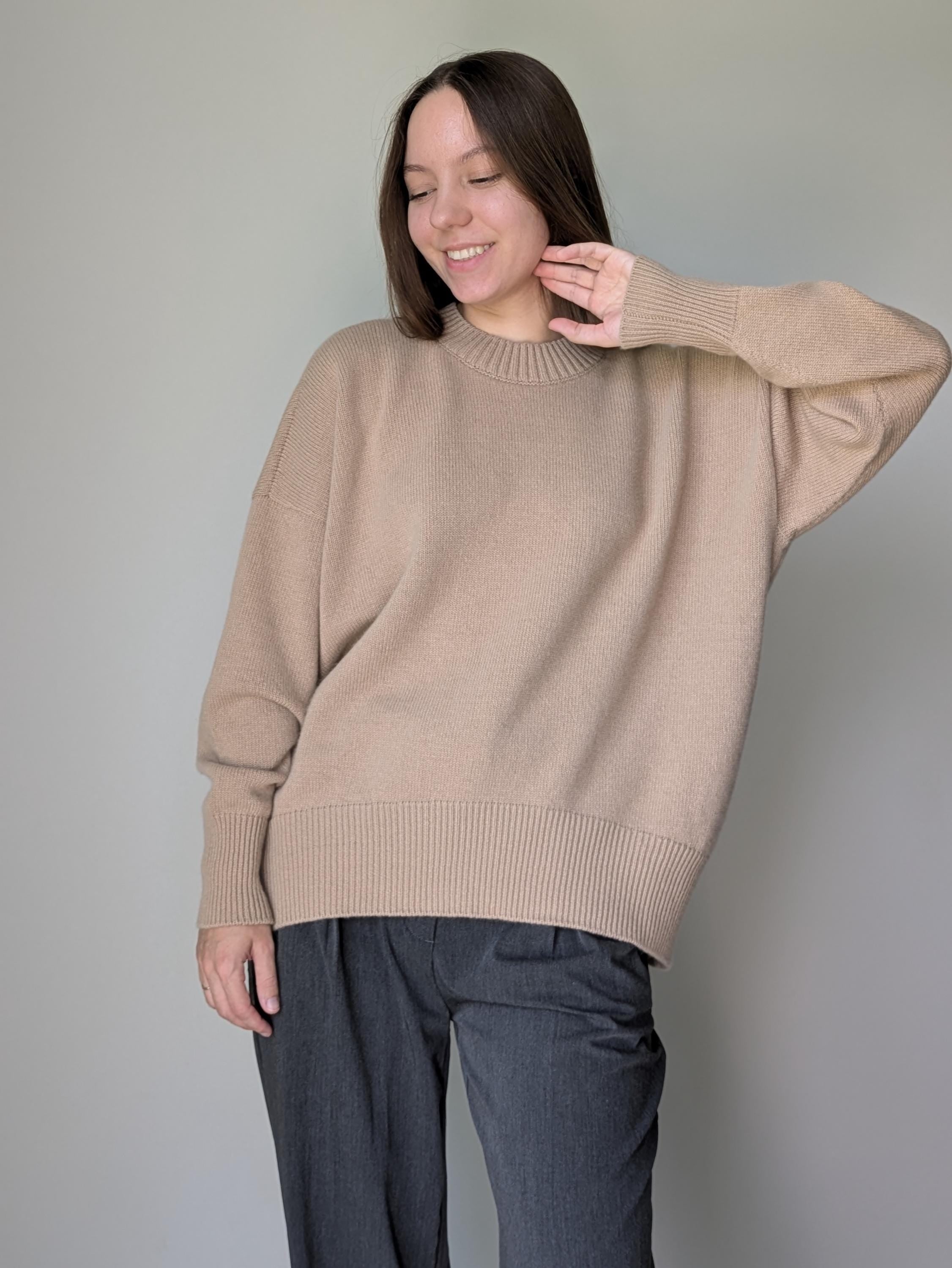 Woman wearing a beige sweater against a plain background