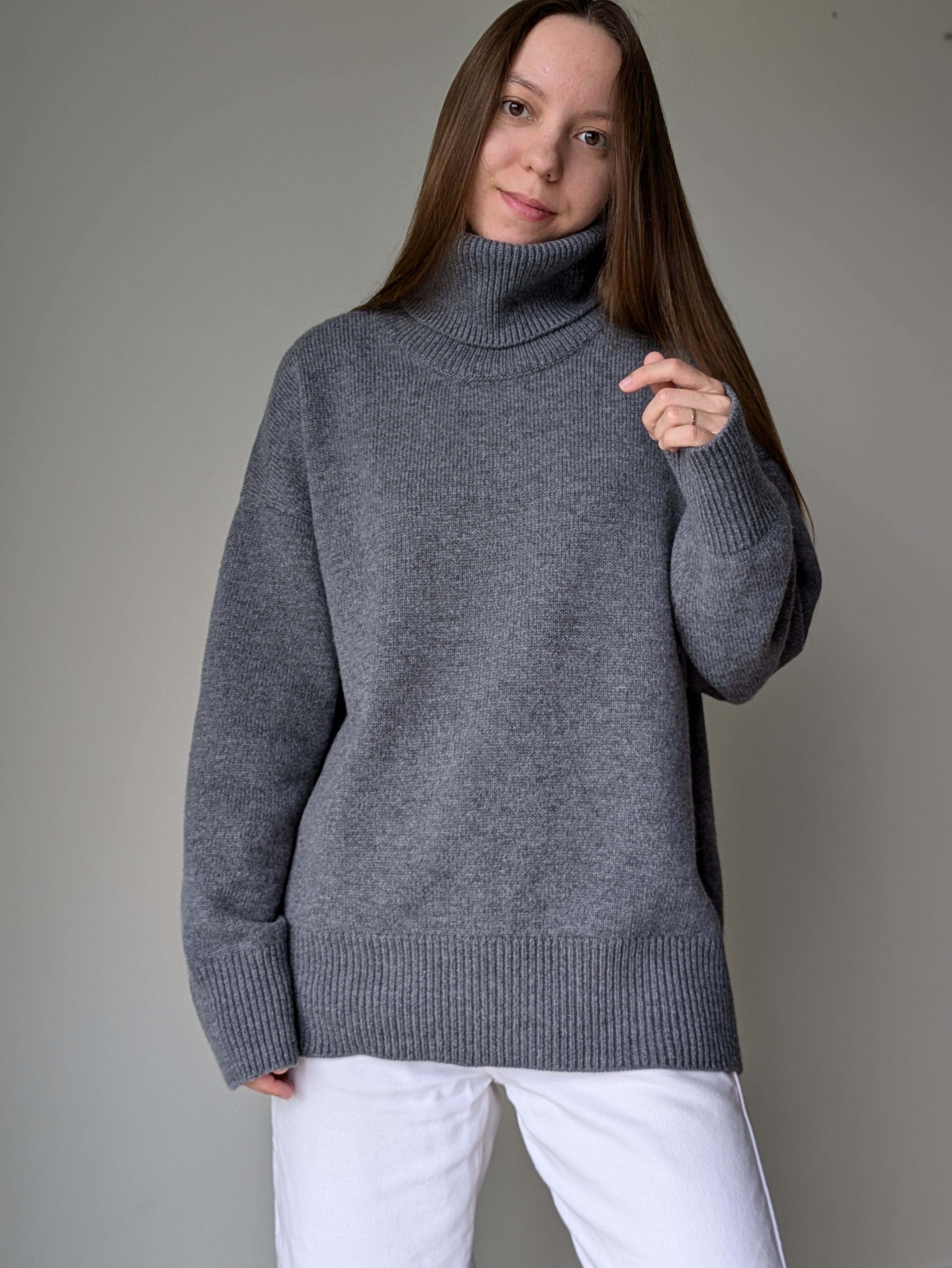 Gray Woman wearing a gray turtleneck sweater against a plain background
