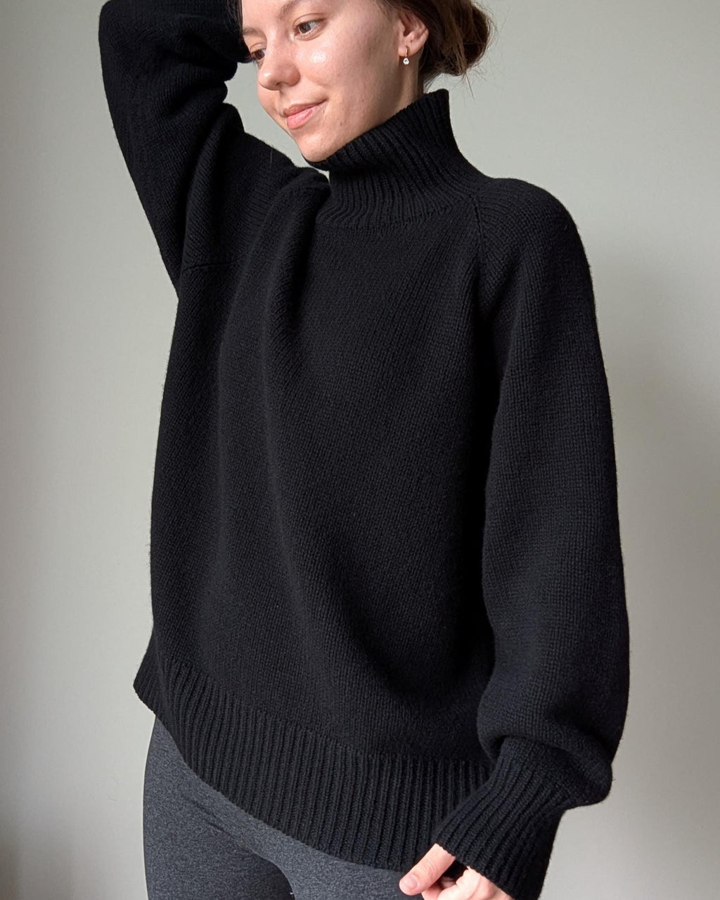 Black Person wearing a black sweater against a plain background