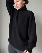 Black Person wearing a black sweater against a plain background