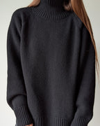Black sweater worn by a person against a neutral background