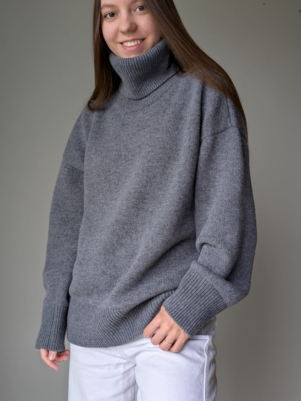 Gray Person wearing a gray turtleneck sweater against a plain background
