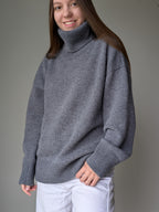 Gray Person wearing a gray turtleneck sweater against a plain background