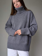 Gray Person wearing a gray turtleneck sweater against a plain background