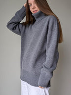 Gray Person wearing a gray sweater against a plain background