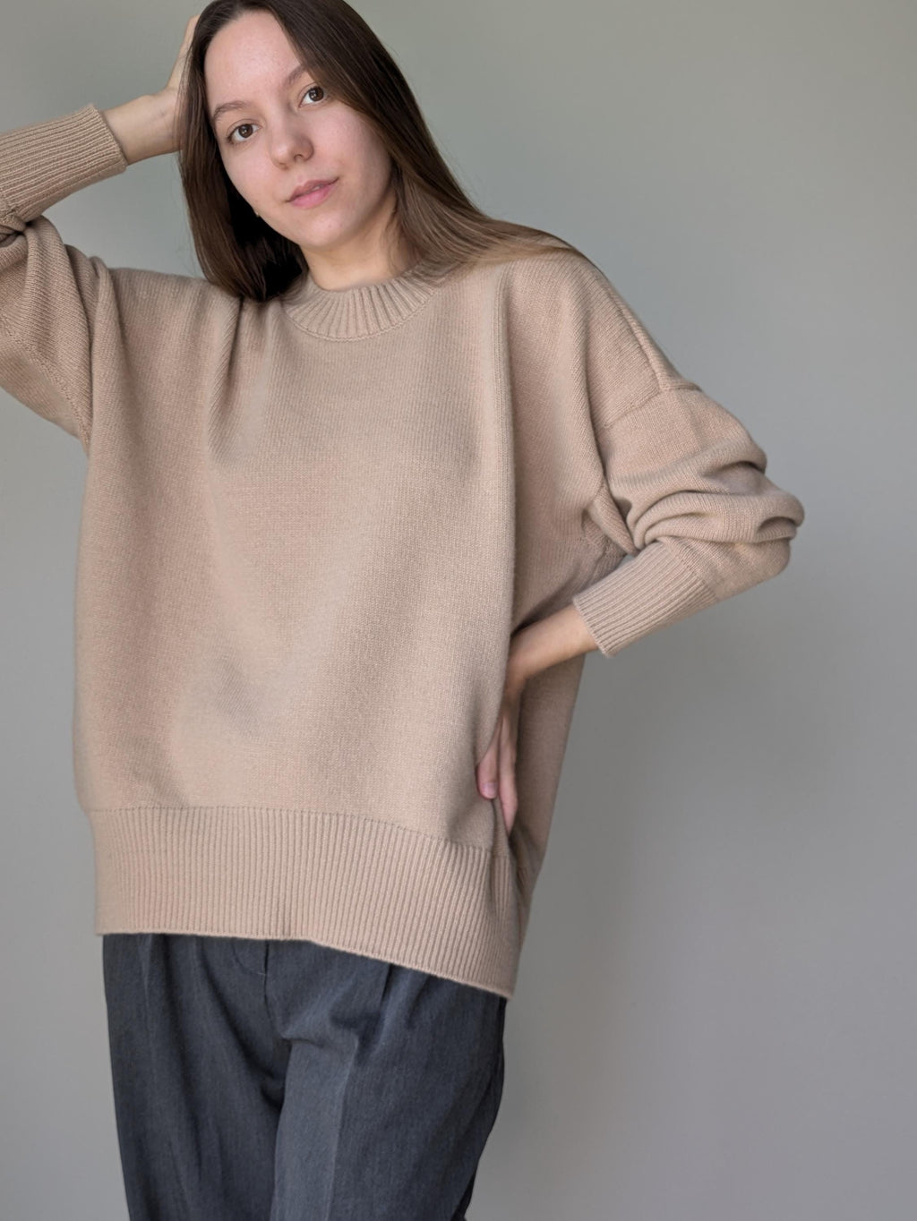 Woman wearing a beige sweater against a plain background
