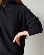 Black Person wearing a black sweater with a neutral background