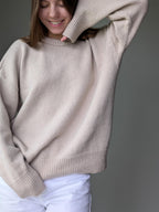 Person wearing a beige sweater against a gray background