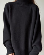 Black turtleneck sweater worn by a person on a plain background