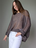 Woman wearing a sheer brown sweater over a gray background