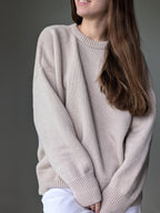 Person wearing a beige sweater against a gray background