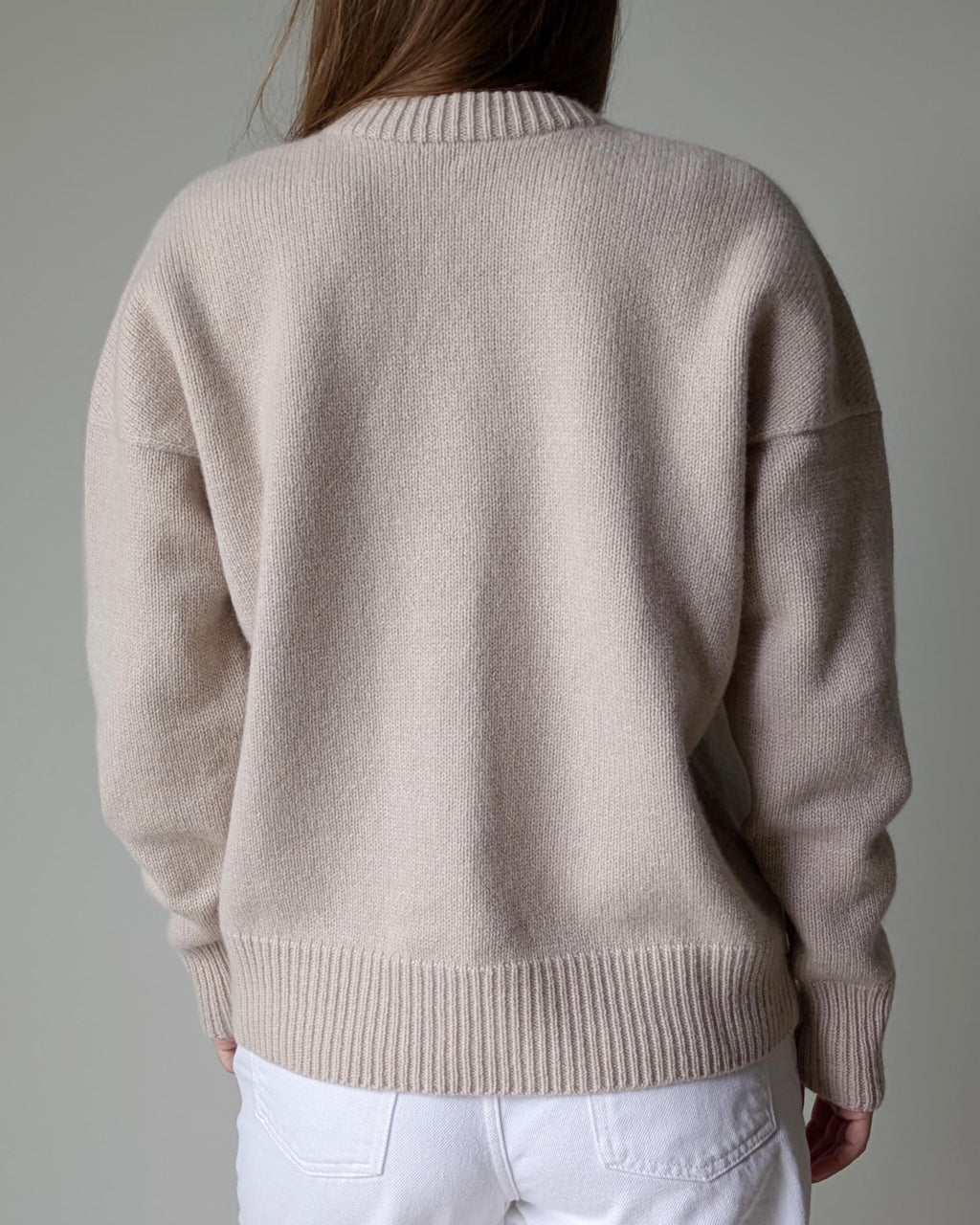 Beige sweater worn by a person on a plain background