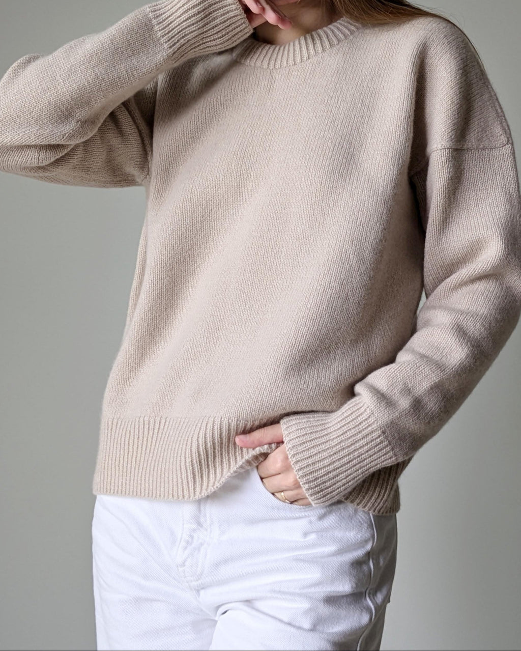 Beige sweater worn by a person on a gray background