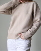 Beige sweater worn by a person on a gray background