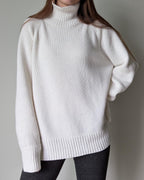 White turtleneck sweater worn by a person on a plain background