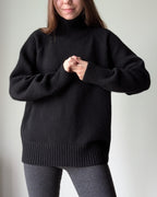 Black Person wearing a black sweater against a plain background
