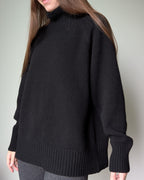 Black Person wearing a black sweater against a plain background