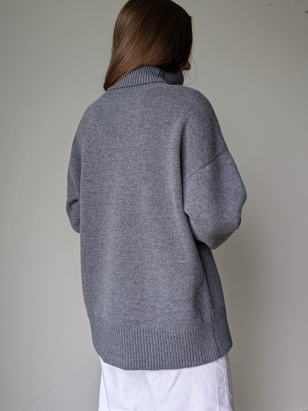Gray Person wearing a gray sweater against a plain background