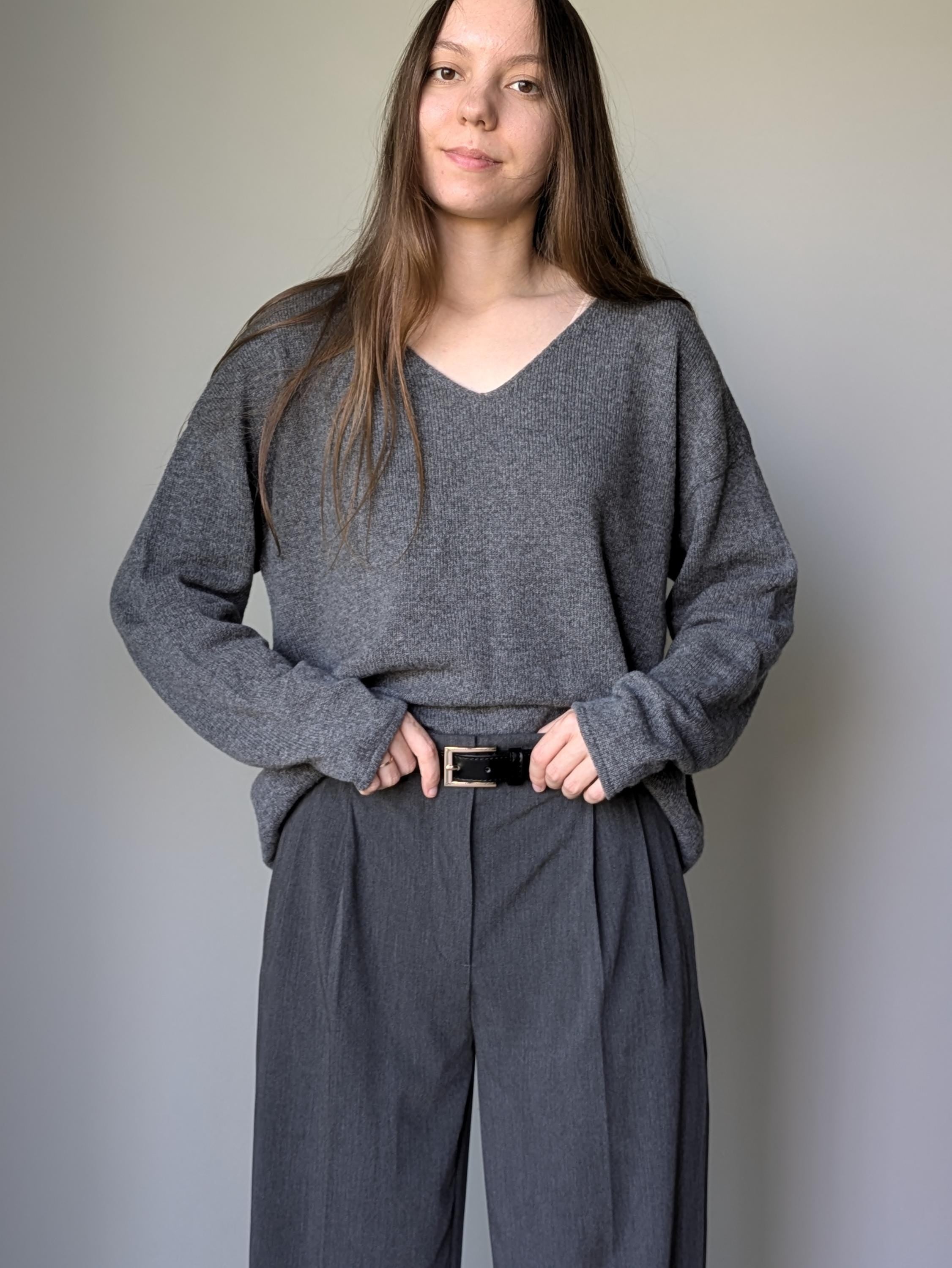 Gray Person wearing a gray sweater and pants against a plain background