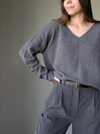 Gray Person wearing a gray sweater and pants against a plain background