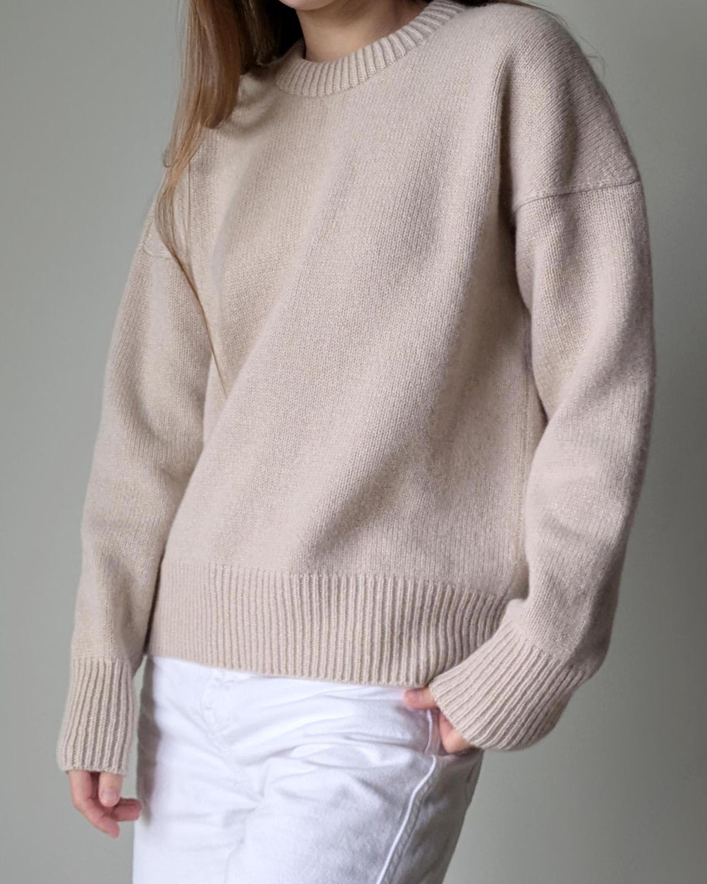 Beige sweater worn by a person on a gray background