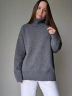 Gray Woman wearing a gray turtleneck sweater against a plain background